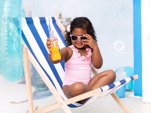 fotos en estudio en Murcia con decorado de verano de playa con bañador y bebiendo una fanta de refresco en la tumbona